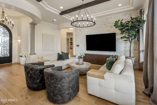 living area featuring arched walkways, a notable chandelier, beam ceiling, and light wood-style floors