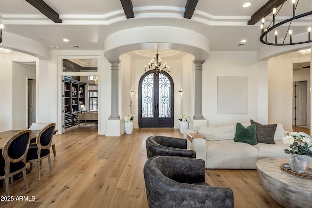 entryway featuring french doors, decorative columns, beam ceiling, and a notable chandelier