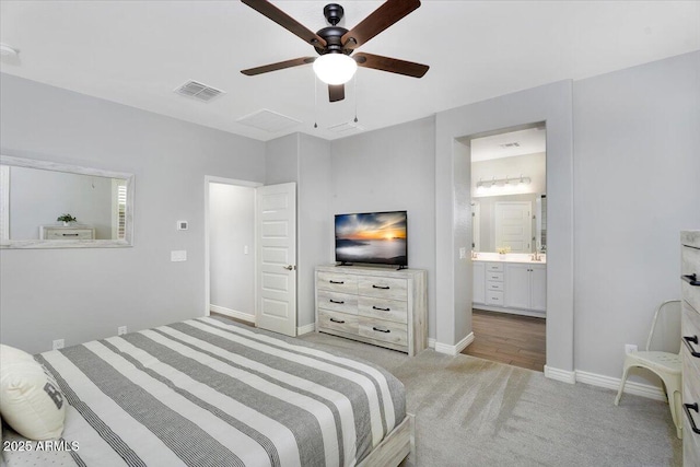 bedroom with visible vents, baseboards, light carpet, ensuite bathroom, and a ceiling fan