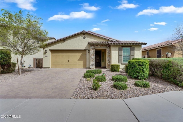 view of front facade with a tiled roof, stucco siding, decorative driveway, a garage, and stone siding