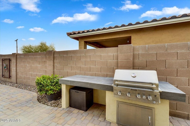 view of patio with area for grilling, a grill, and fence