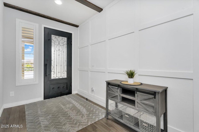 foyer with beamed ceiling, baseboards, dark wood-type flooring, and a decorative wall