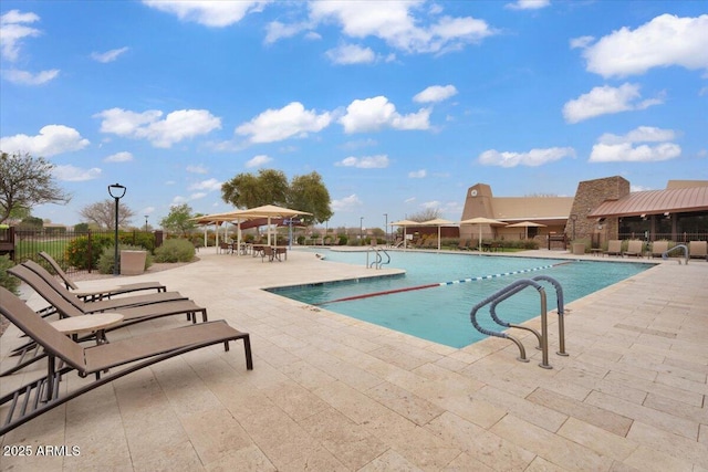 pool with a patio area and fence