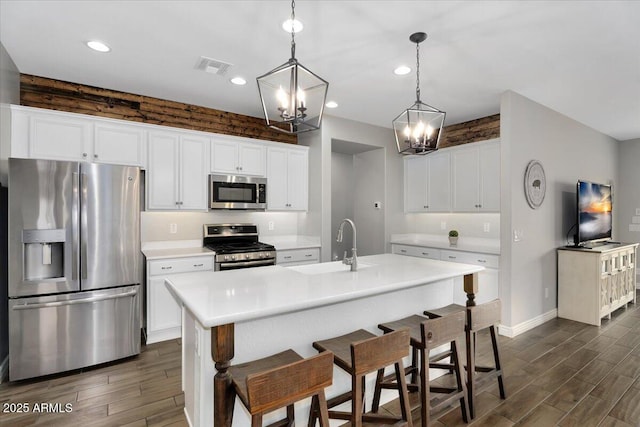 kitchen with wood finish floors, visible vents, a notable chandelier, a sink, and stainless steel appliances