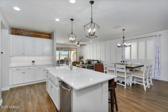 kitchen with light wood finished floors, a sink, white cabinetry, and stainless steel dishwasher