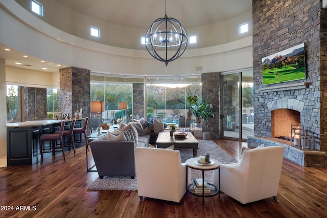 living room featuring a fireplace, a high ceiling, a chandelier, and dark hardwood / wood-style floors