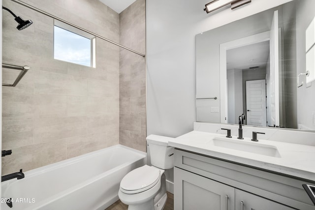 full bathroom featuring tiled shower / bath, vanity, and toilet