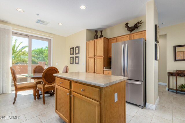 kitchen featuring stainless steel fridge, a kitchen island, and light tile patterned flooring