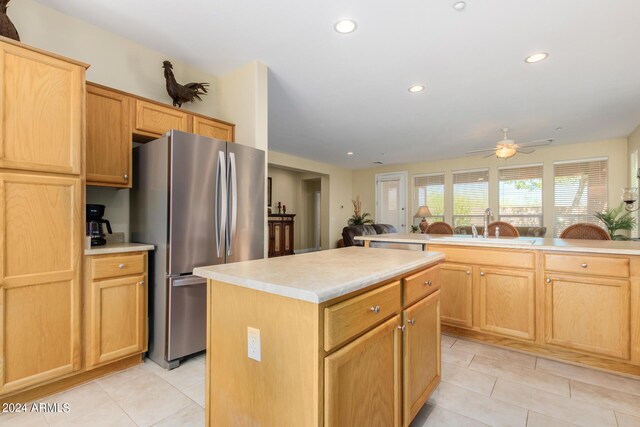 kitchen with a center island, sink, stainless steel fridge, light tile patterned flooring, and ceiling fan