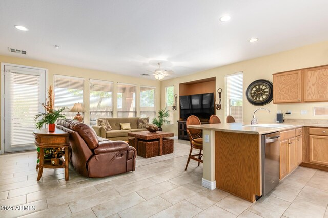 kitchen with light tile patterned floors, dishwasher, kitchen peninsula, sink, and ceiling fan