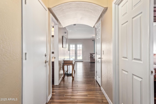 hall featuring lofted ceiling, dark wood-type flooring, a textured ceiling, and french doors