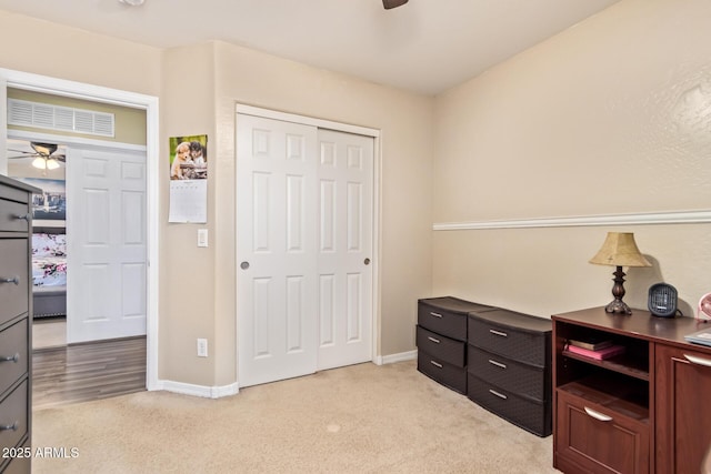 bedroom featuring light carpet, ceiling fan, and a closet