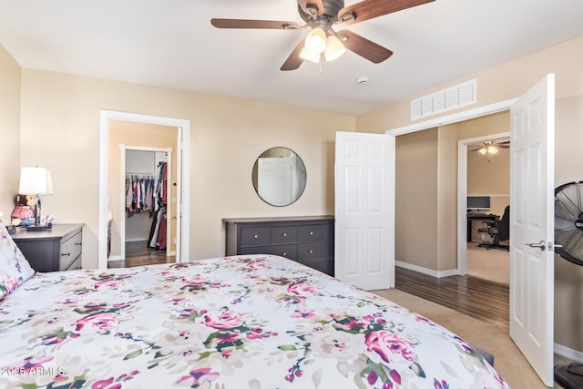 bedroom featuring ceiling fan, a walk in closet, and a closet