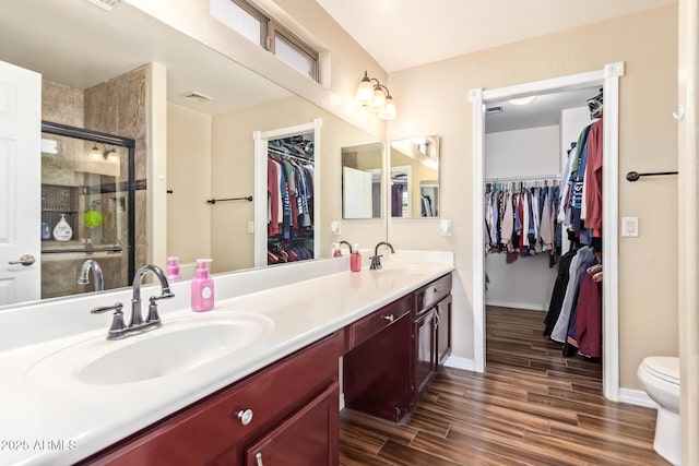 bathroom featuring vanity, hardwood / wood-style floors, a shower with shower door, and toilet