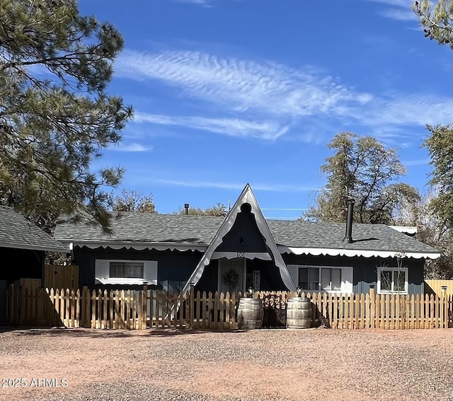 view of front of home with roof with shingles and fence