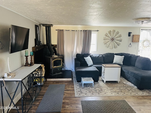 living area with a textured ceiling, a wood stove, wood finished floors, and a healthy amount of sunlight