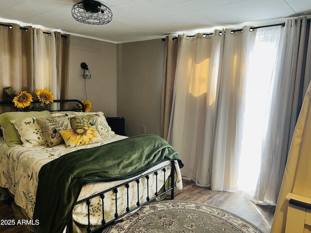 bedroom with ornamental molding and wood finished floors