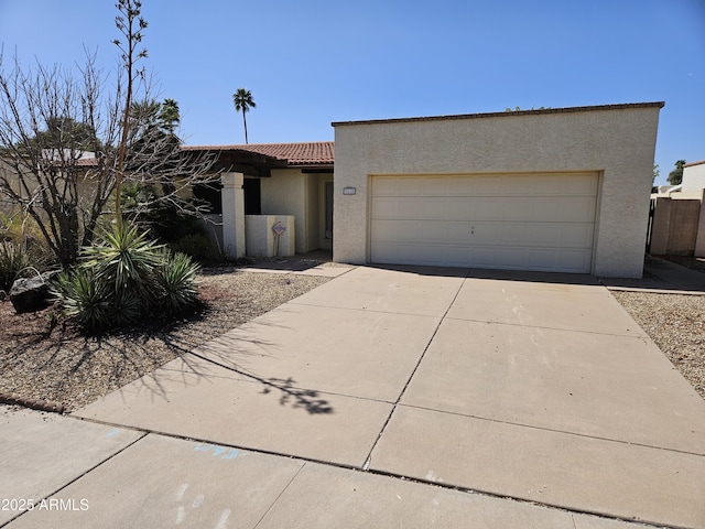 view of front of home featuring concrete driveway, a tiled roof, a garage, and stucco siding