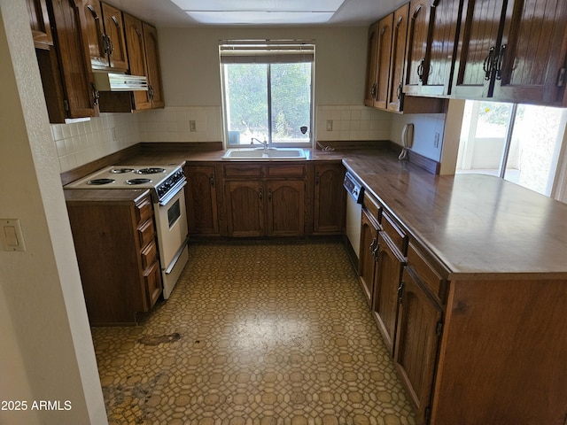 kitchen featuring a sink, under cabinet range hood, tasteful backsplash, white appliances, and light floors