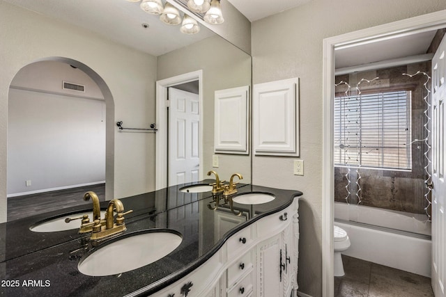 bathroom featuring toilet, double vanity, and tub / shower combination