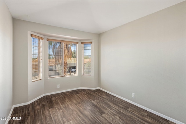 spare room with dark wood-style floors and baseboards