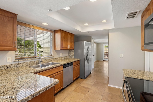 kitchen featuring stainless steel appliances, a sink, brown cabinetry, baseboards, and recessed lighting