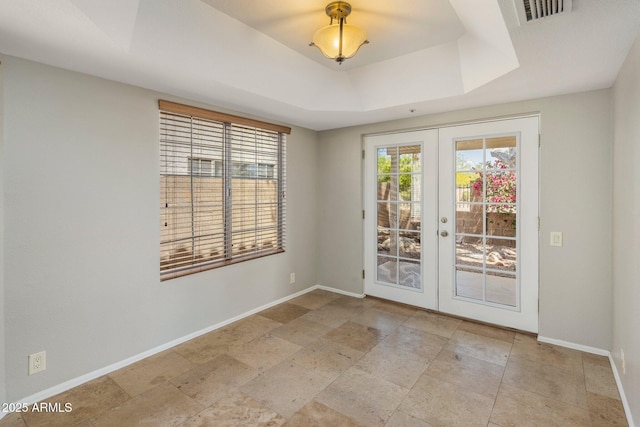 spare room featuring french doors, a raised ceiling, and baseboards