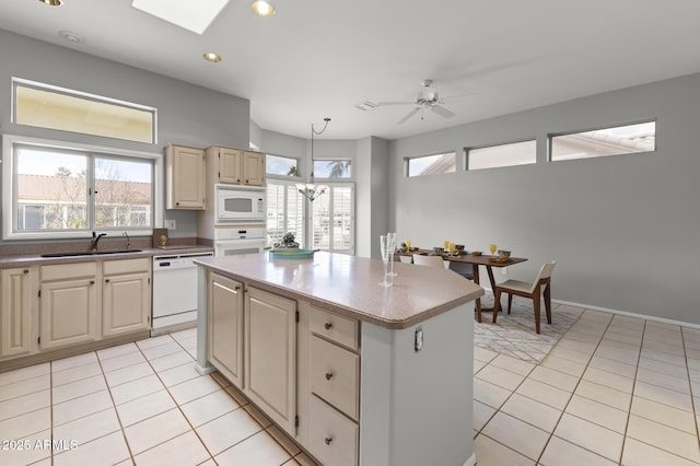 kitchen featuring a kitchen island, a skylight, sink, light tile patterned floors, and white appliances