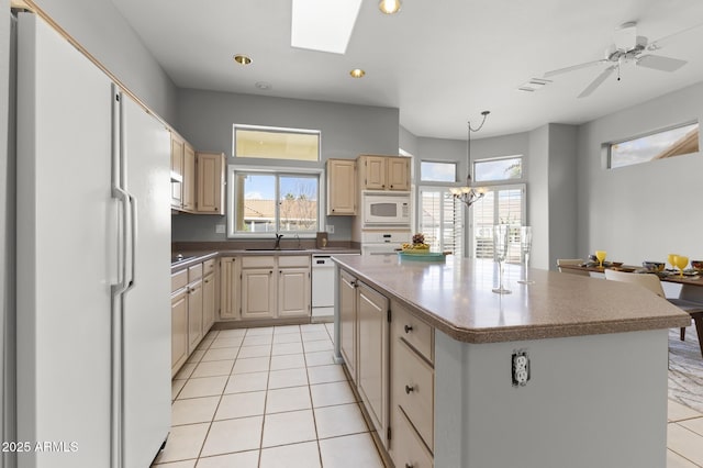 kitchen featuring a skylight, sink, a center island, light tile patterned floors, and white appliances