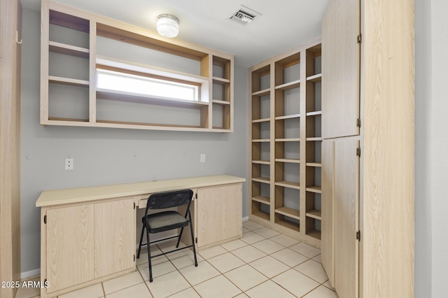 unfurnished office featuring light tile patterned floors and built in desk