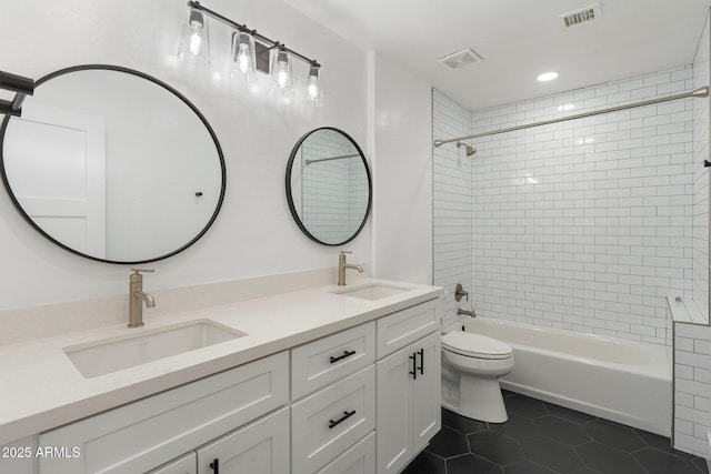 full bathroom with tile patterned flooring, vanity, tiled shower / bath combo, and toilet