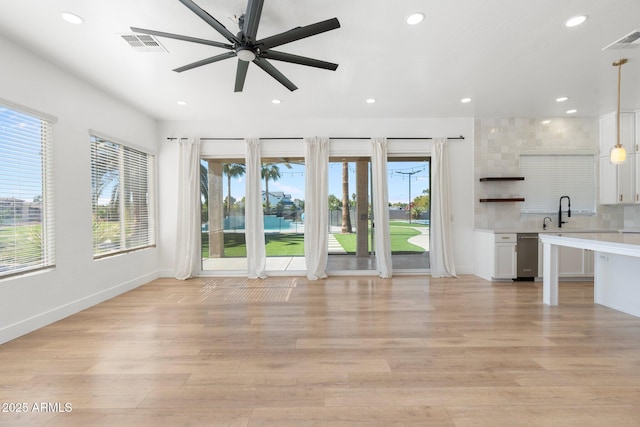 unfurnished living room featuring ceiling fan, sink, and light hardwood / wood-style flooring