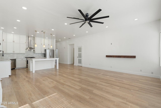 unfurnished living room with sink, light hardwood / wood-style flooring, and ceiling fan