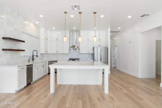 kitchen with decorative light fixtures, a center island, white cabinets, and appliances with stainless steel finishes