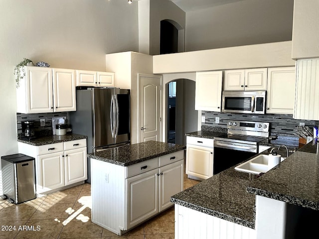 kitchen with a center island, white cabinets, a high ceiling, stainless steel appliances, and light tile patterned flooring