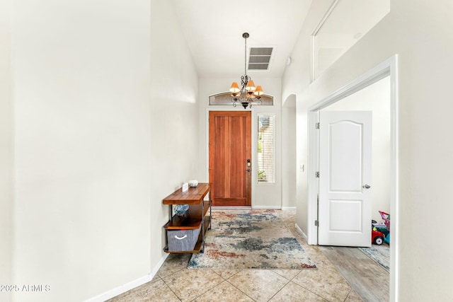 tiled foyer entrance with an inviting chandelier