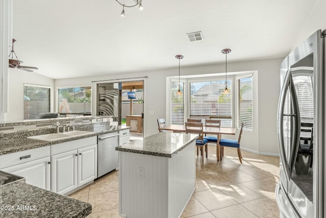 kitchen featuring a center island, white cabinetry, stainless steel appliances, sink, and hanging light fixtures