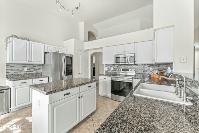 kitchen featuring white cabinets, stainless steel appliances, sink, light tile patterned flooring, and high vaulted ceiling