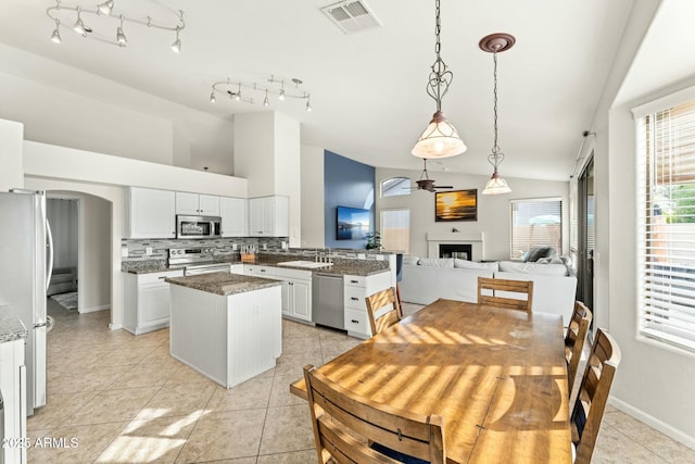 kitchen with white cabinets, a kitchen island, pendant lighting, backsplash, and stainless steel appliances