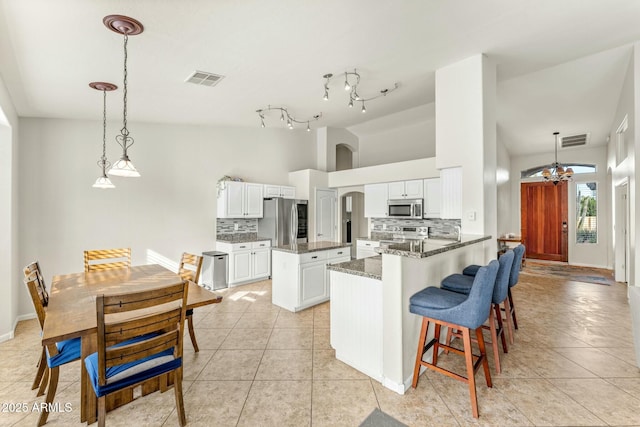 kitchen featuring white cabinets, stainless steel appliances, kitchen peninsula, and backsplash