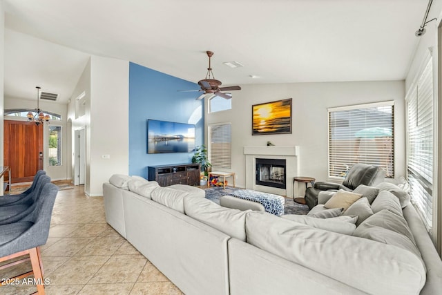 tiled living room with ceiling fan with notable chandelier, a healthy amount of sunlight, and lofted ceiling