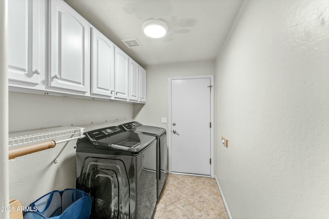 laundry room with light tile patterned floors, cabinets, and washer and clothes dryer