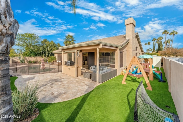 rear view of property with an outdoor living space, a playground, exterior kitchen, a yard, and a patio area