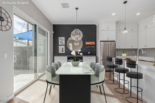 dining area featuring a chandelier, sink, and light hardwood / wood-style flooring