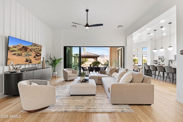 living room with sink, light hardwood / wood-style floors, and ceiling fan