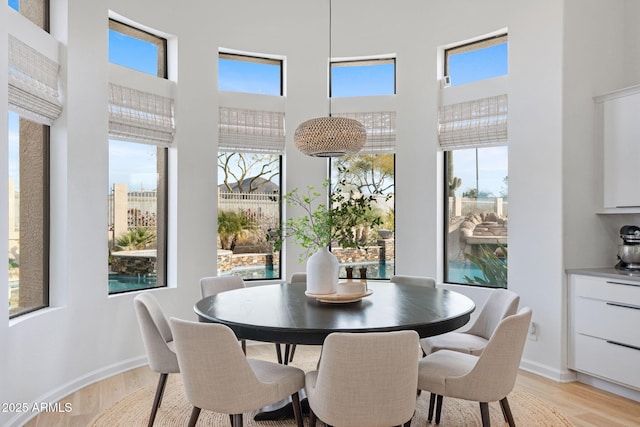 dining room featuring a towering ceiling and light hardwood / wood-style floors