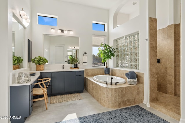 bathroom featuring independent shower and bath, vanity, a towering ceiling, and tile patterned floors