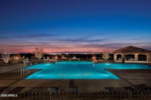 pool at dusk with a patio area