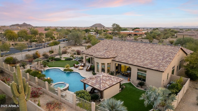 pool at dusk with a patio area and an in ground hot tub