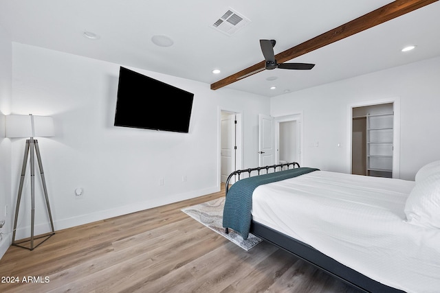 bedroom with beam ceiling, light hardwood / wood-style floors, and ceiling fan